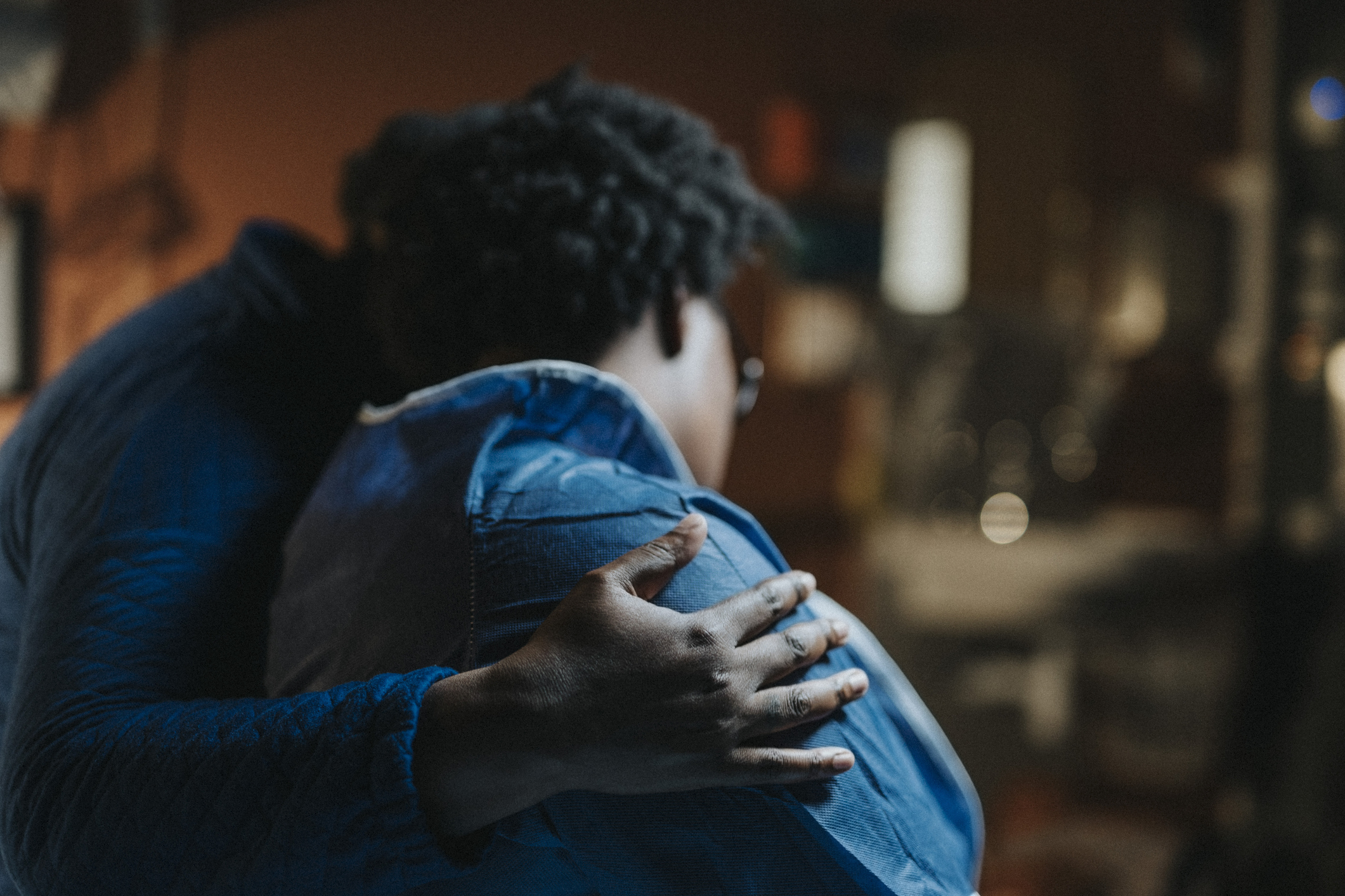 Two people embrace in a comforting hug. Their faces are not visible