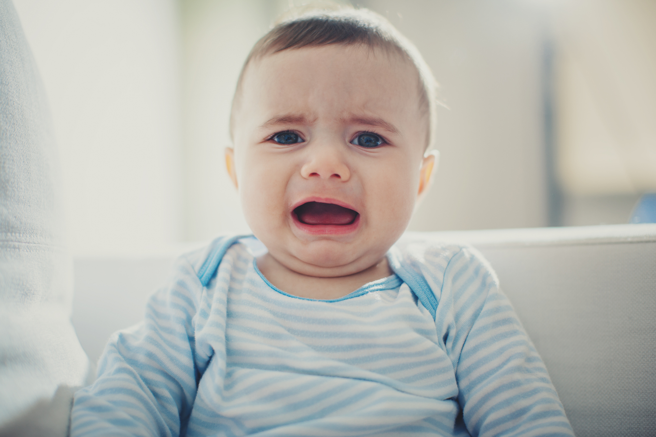 Crying baby wearing a striped outfit