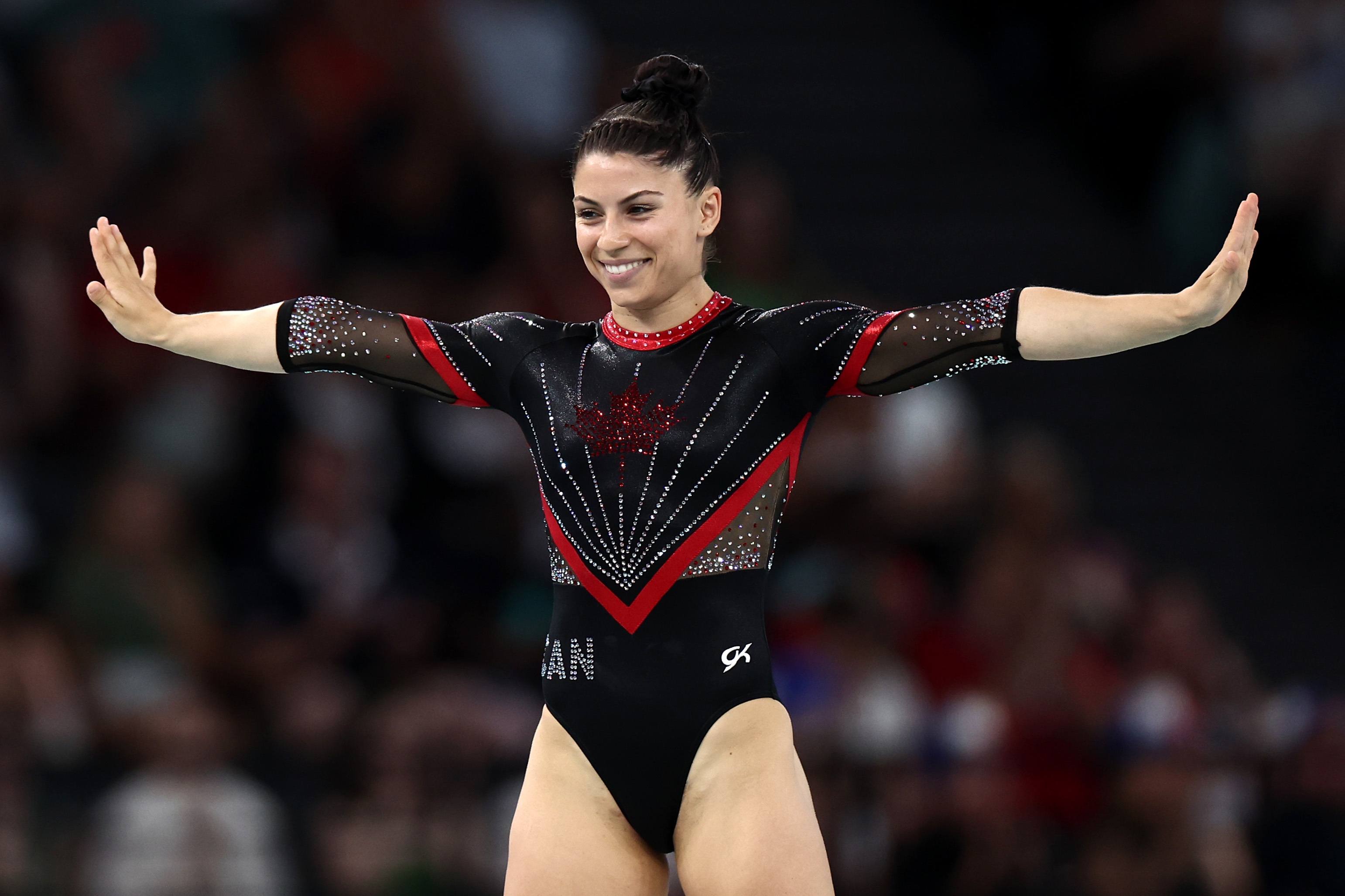 Gymnastics champion on the balance beam, wearing a black and red leotard with sparkling details, arms outstretched and smiling