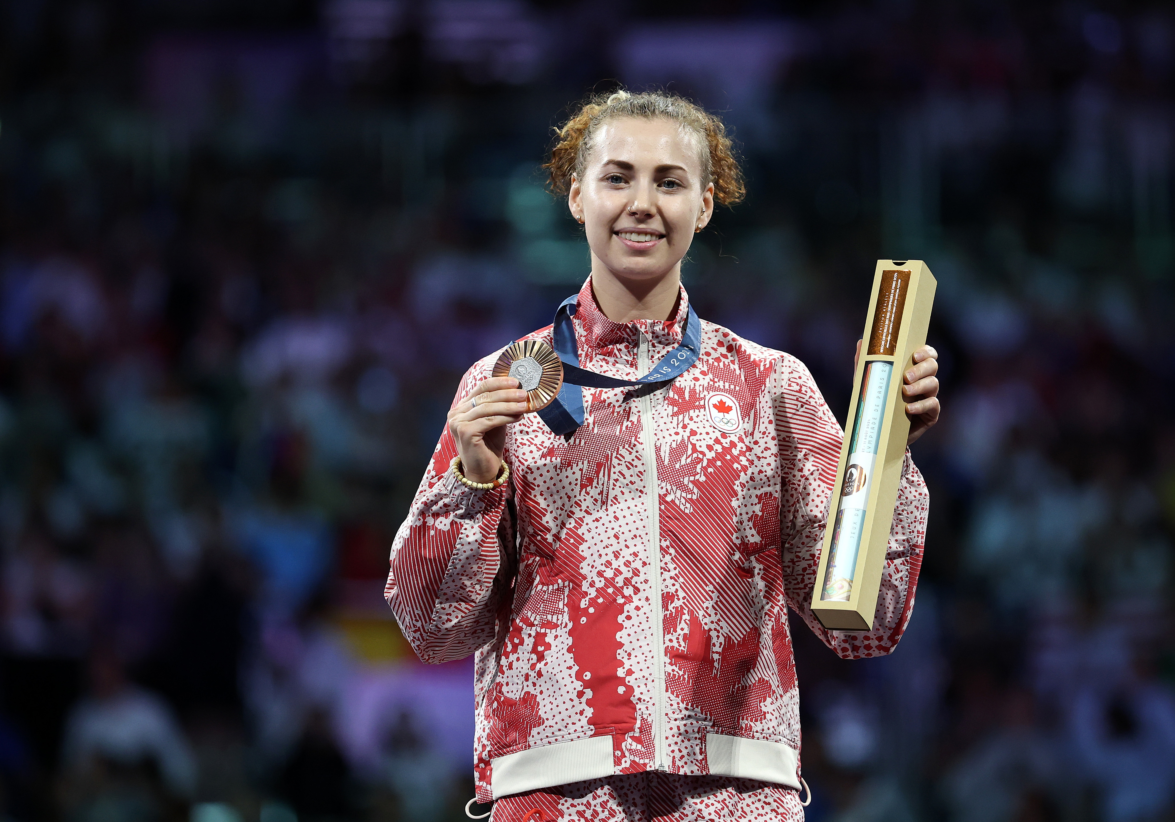 Athlete holding a medal and trophy on a sports podium