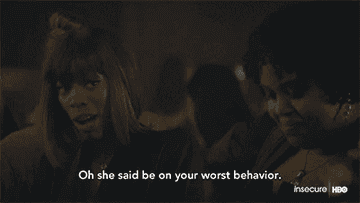 Issa Rae, with a short bob haircut, and Yvonne Orji are talking in a dimly lit setting. Text reads, "Oh she said be on your worst behavior."