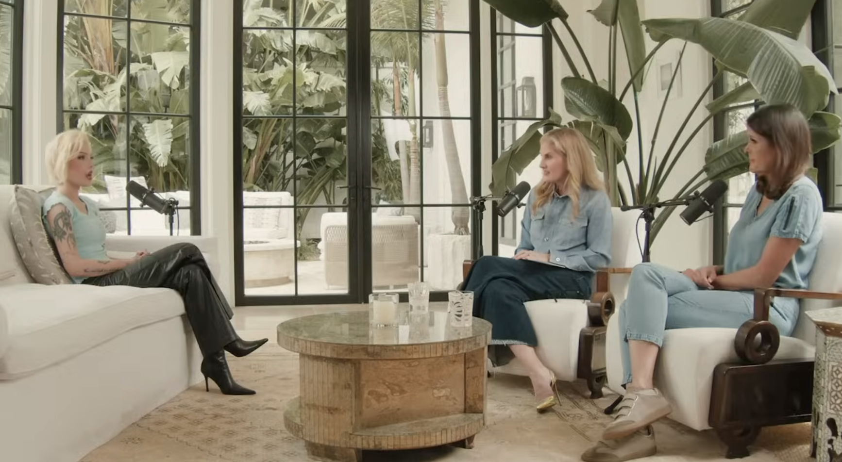 Three women, including Selena Gomez, sit in a modern, plant-filled living room setting, engaged in a conversation
