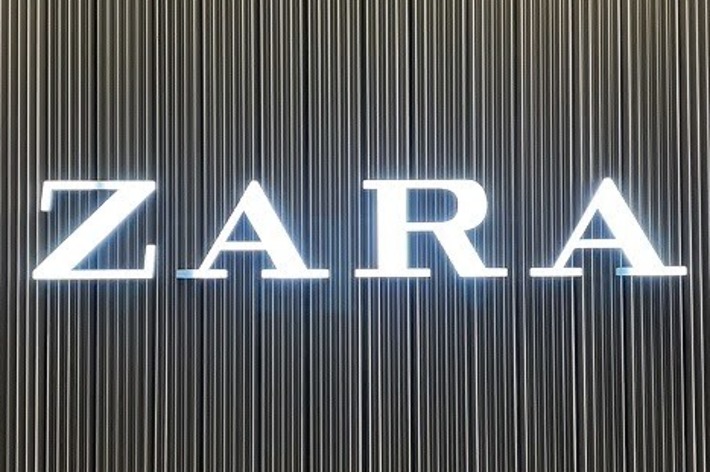 Zara store sign with bright white letters against a vertically lined backdrop