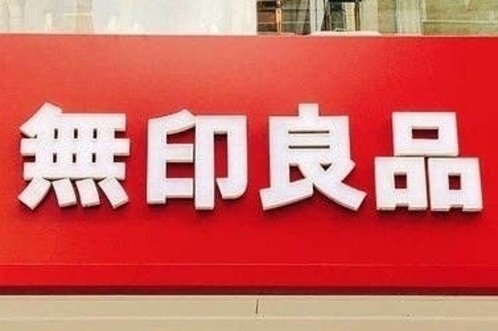 Storefront with large red signage displaying Japanese characters, likely indicating a Muji store