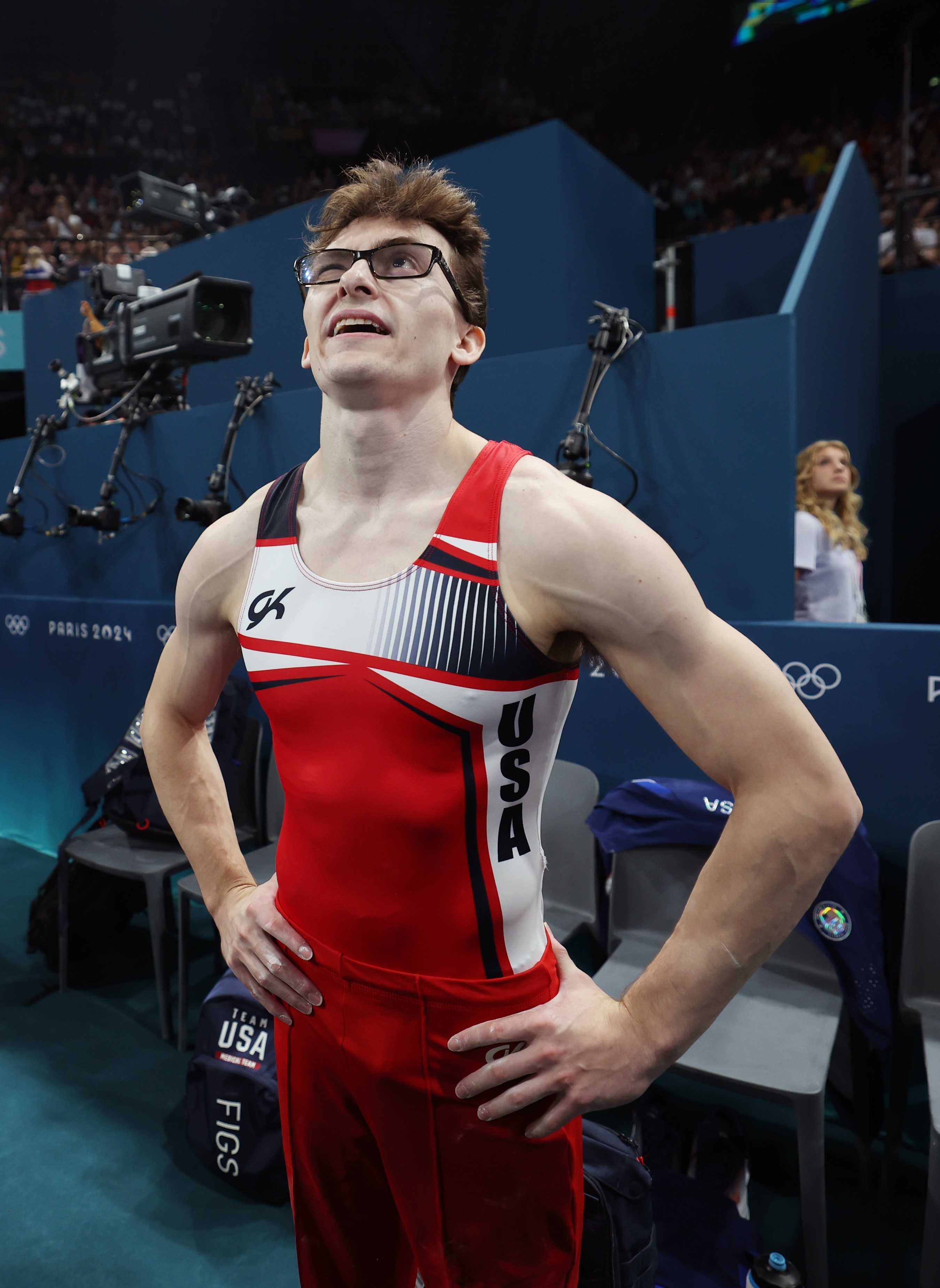 Olympic gymnast Fred Richard stands in a competition arena, wearing a sleeveless athletic outfit with "USA" on the side
