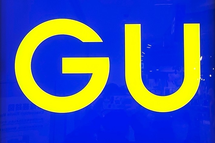 A blue square sign with the yellow letters &ldquo;GU&rdquo; in the center