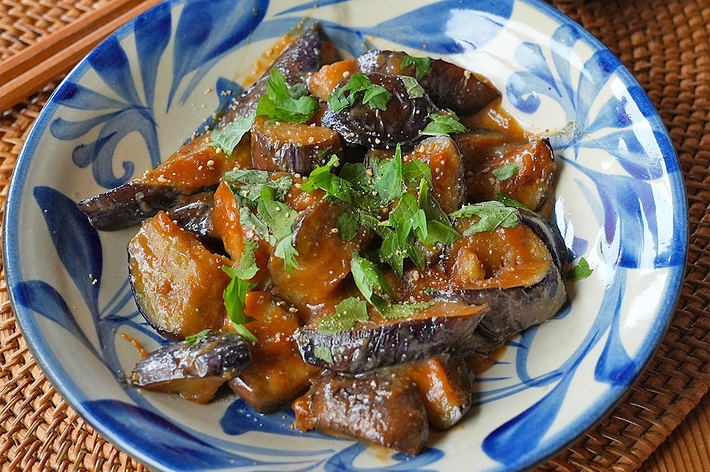 ナスの炒め物とご飯の盛られた食卓の一部。
