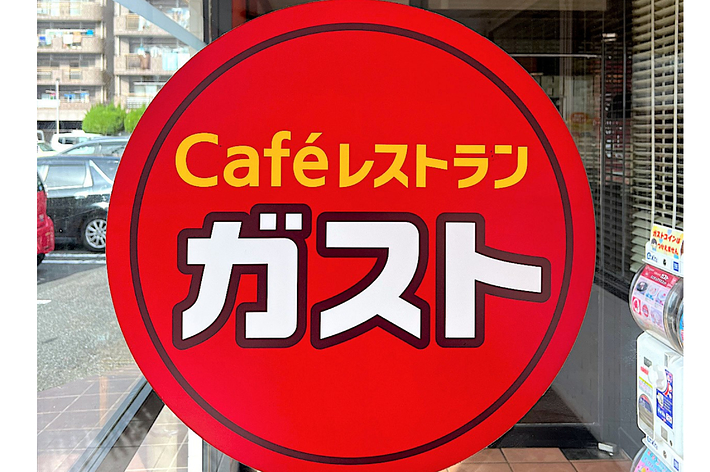 A large black sign with yellow Japanese text and two green shoes at the top. The sign features a red circle above the shoes