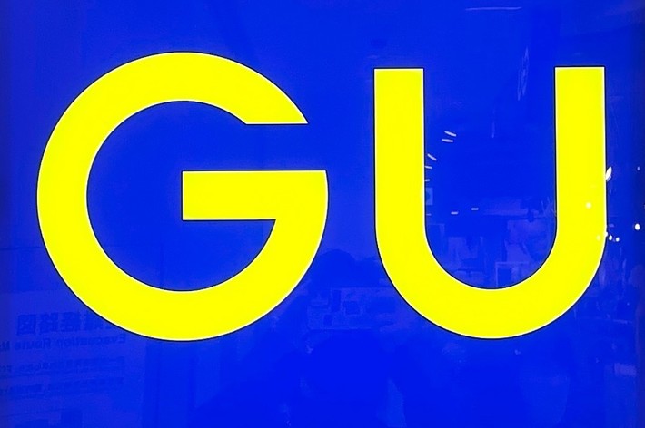 A square sign with the letters &ldquo;GU&rdquo; in bold yellow font on a blue background