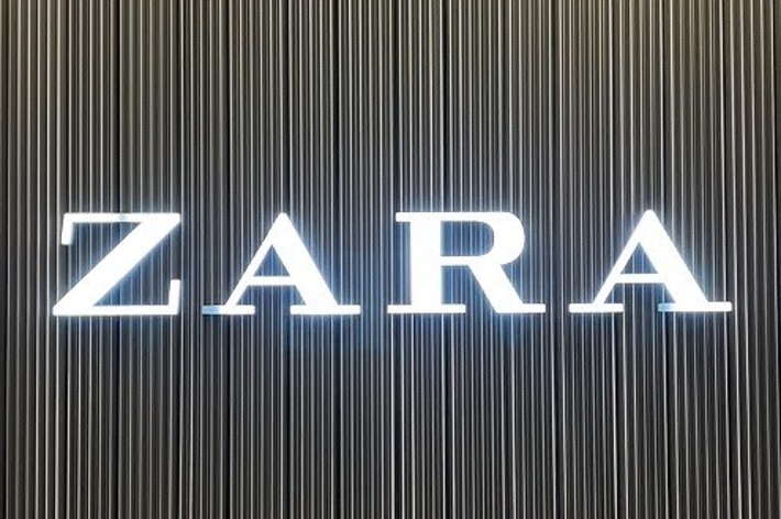 ZARA store entrance with the brand&rsquo;s name illuminated against a striped wall background