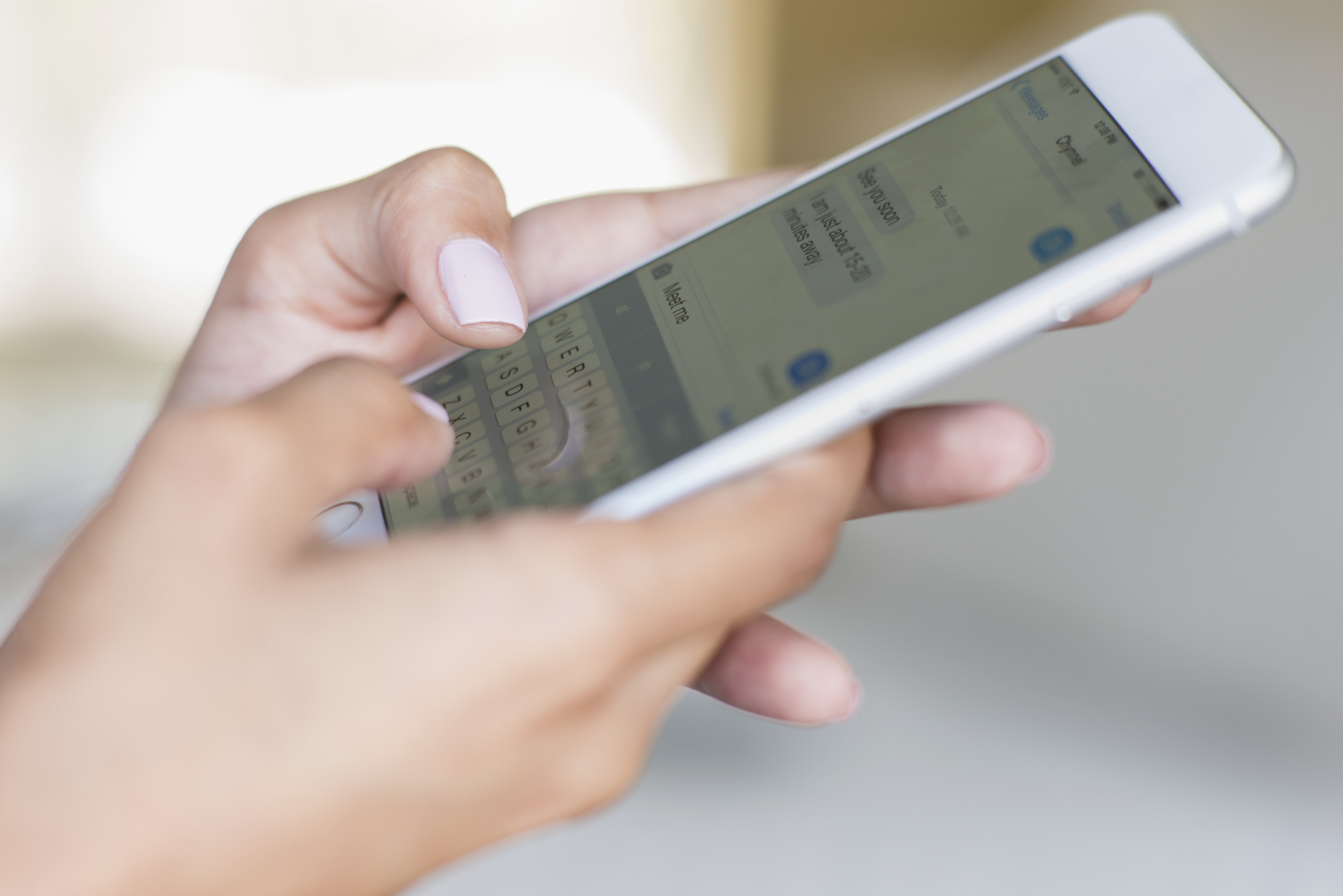 Close-up of someone's hands typing on a smartphone, composing a text message