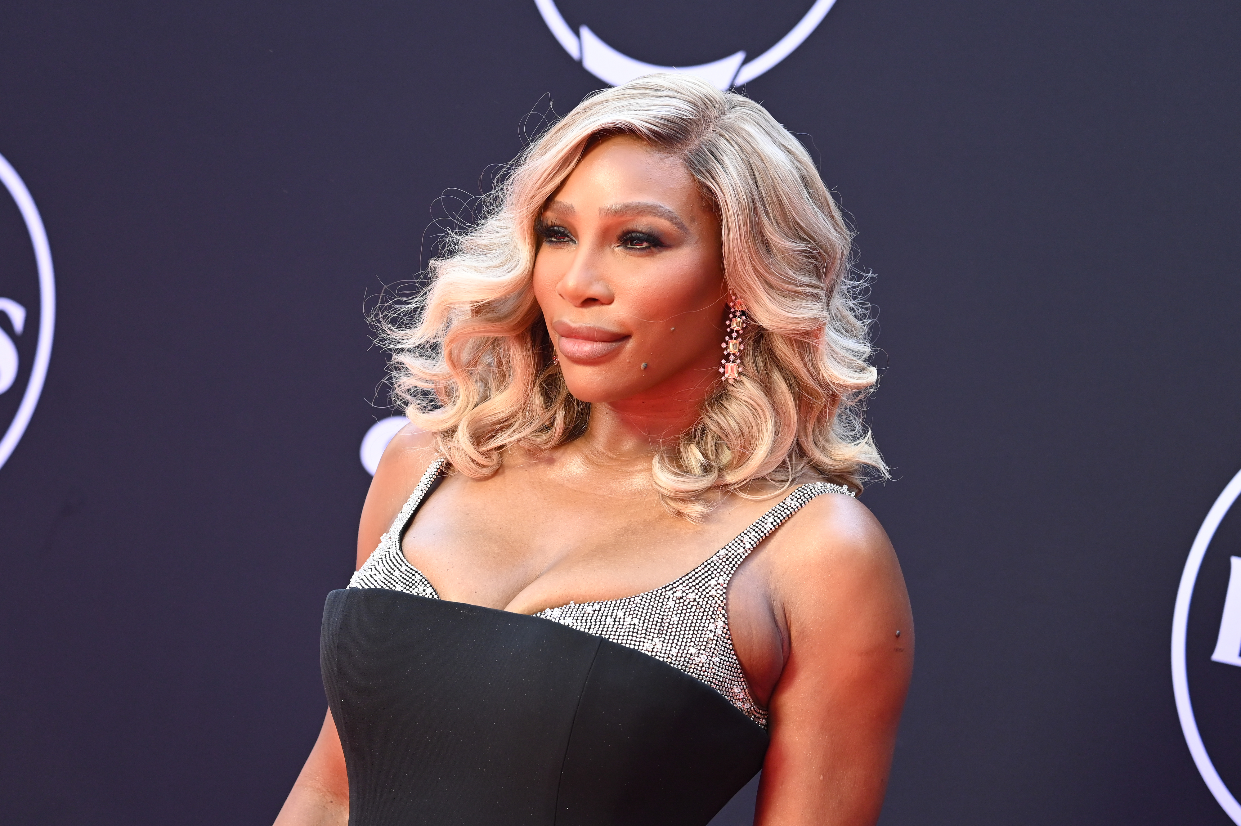Serena Williams on the red carpet wearing a black gown with shimmering silver accents
