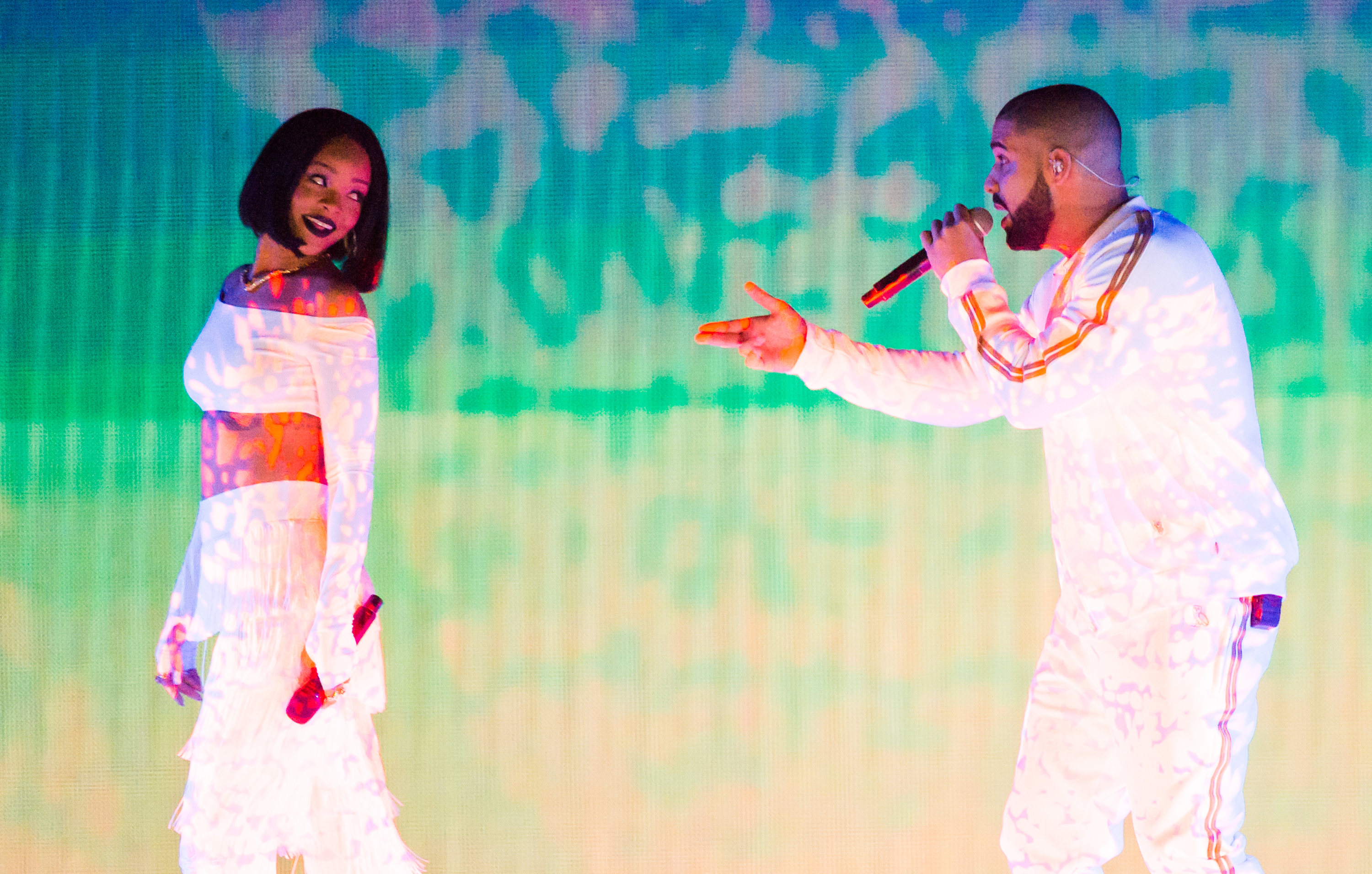 Rihanna in an off-shoulder outfit and Drake in a tracksuit performing on stage
