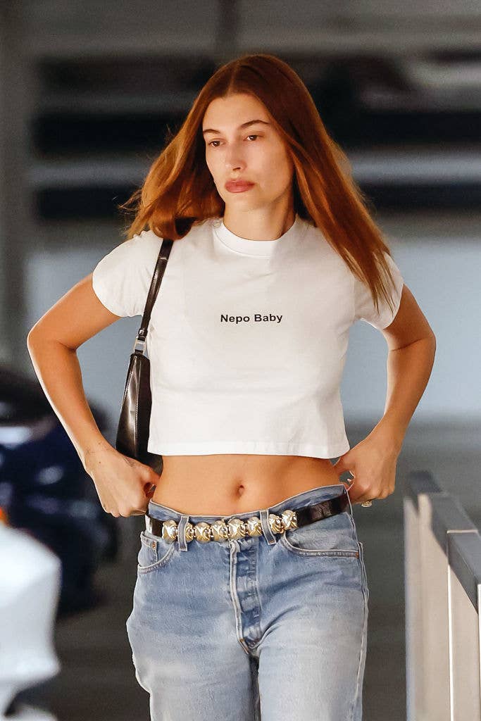 Hailey Bieber wears a "Nepo Baby" t-shirt and jeans while walking