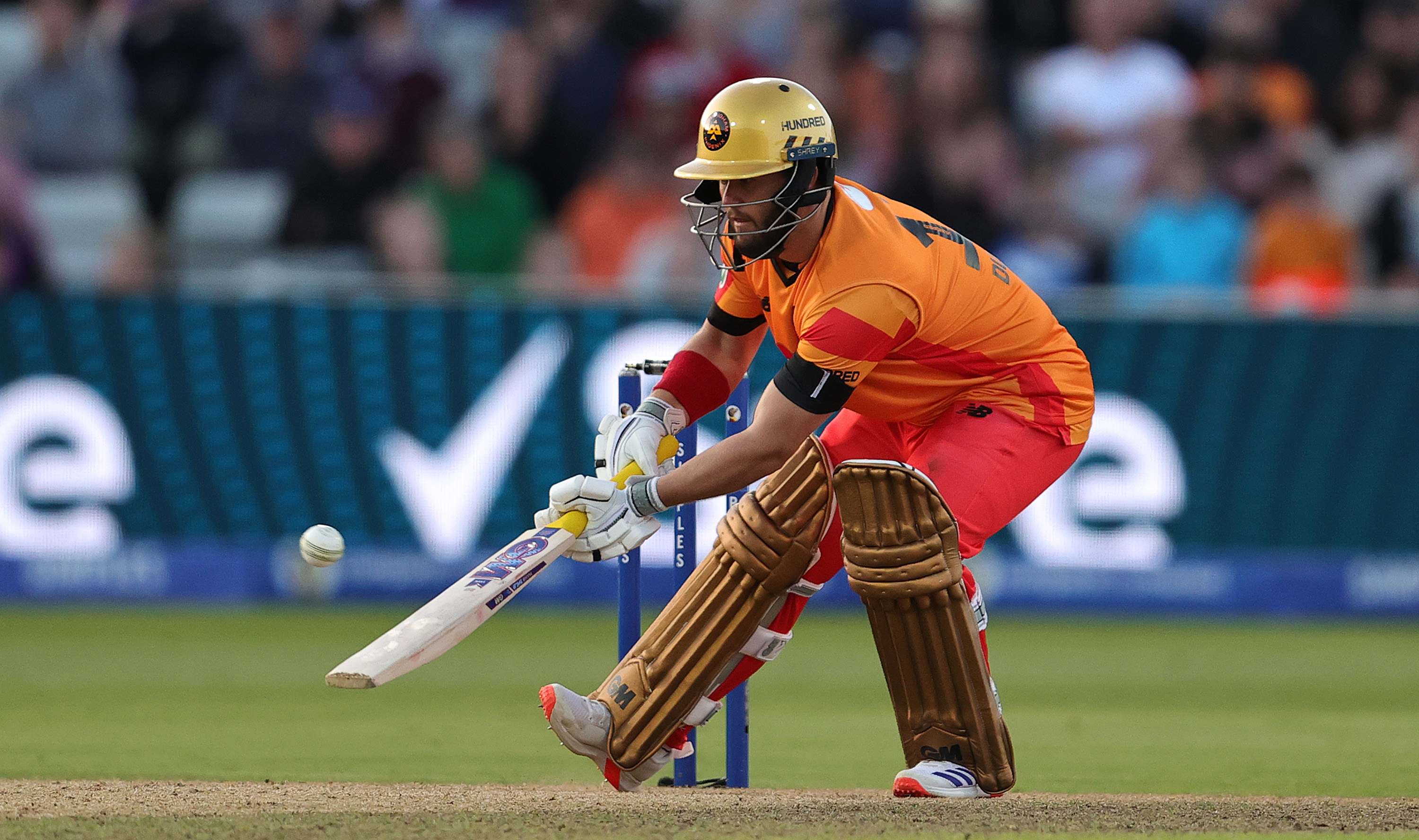 Cricketer Mohammad Rizwan batting on the field, wearing a helmet and protective gear, focusing on hitting the ball
