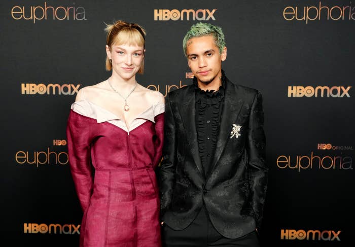 Hunter Schafer and Dominic Fike on the red carpet at the "Euphoria" HBO Max event. Hunter wears an off-shoulder outfit, and Dominic wears a black suit