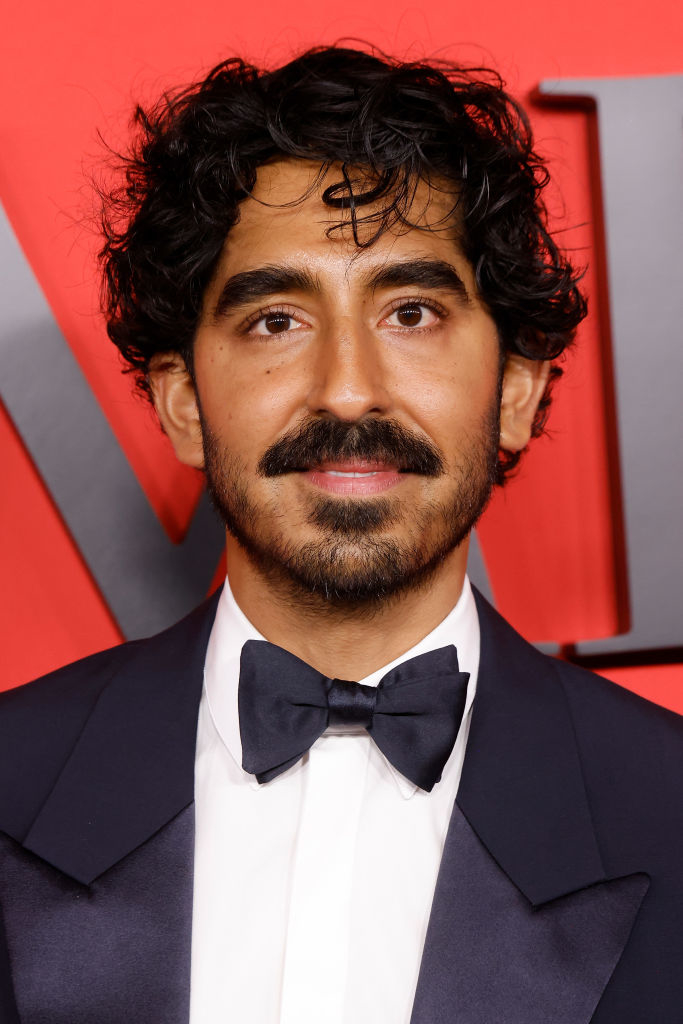 Dev Patel on the red carpet in a formal dark suit and bow tie