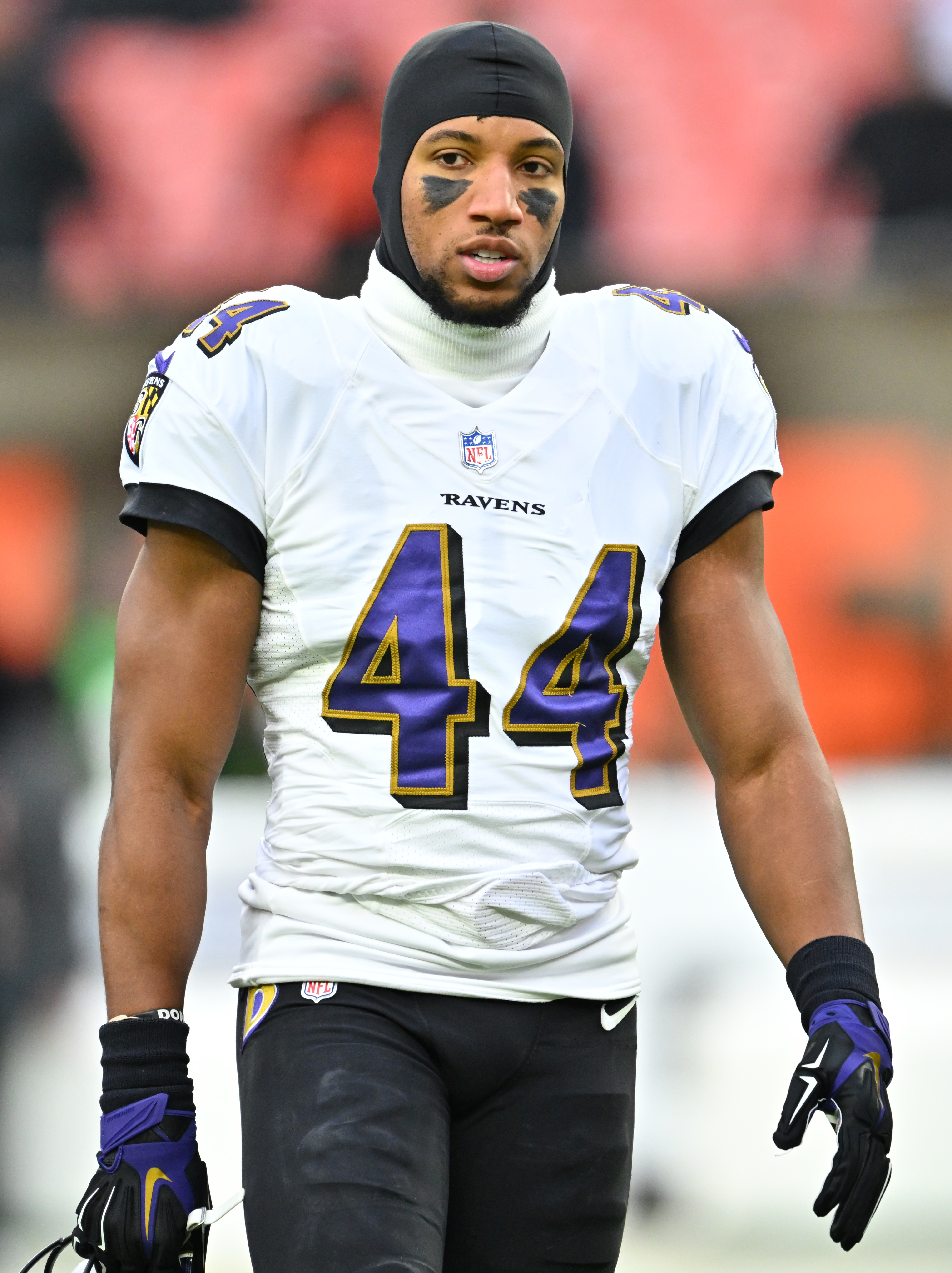 A football player from the Baltimore Ravens, wearing number 44, stands on the field wearing a helmet liner, eye black, and full uniform