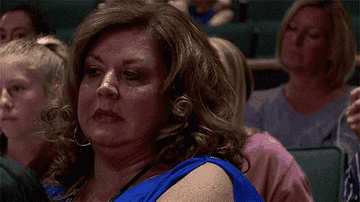 Abby Lee Miller with curled shoulder-length hair, scowls.