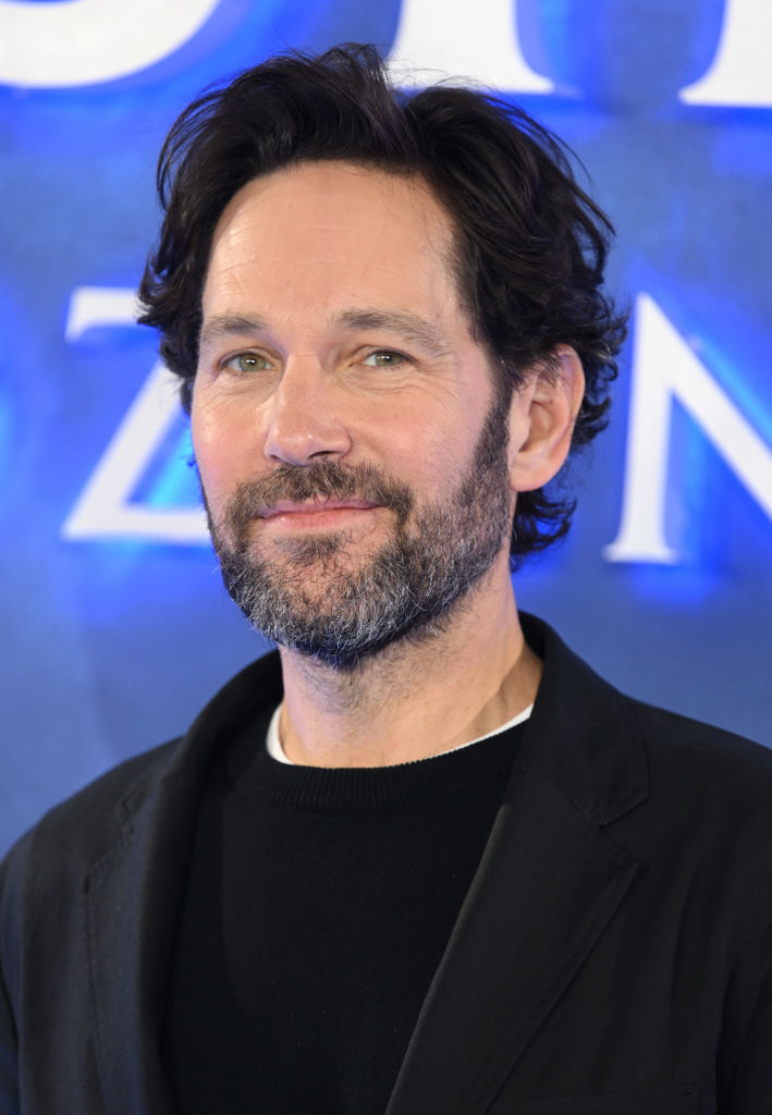 Paul Rudd, wearing a black blazer and black shirt, smiling at a promotional event