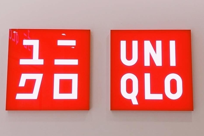 Red signs with white text displaying &ldquo;UNIQLO&rdquo; in Japanese characters on the left and English letters on the right
