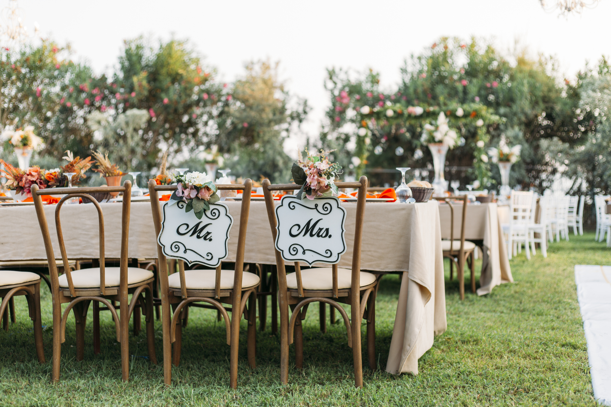 Outdoor wedding reception with two wooden chairs labeled &quot;Mr&quot; and &quot;Mrs&quot;