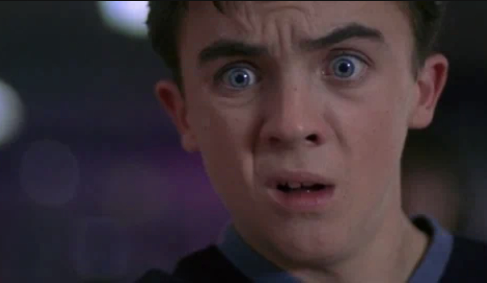 Close-up of a young boy with wide blue eyes and a horrified expression on his face, wearing a shirt