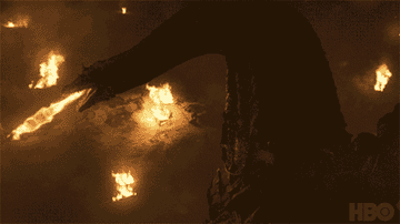 Dragón de la serie Game of Thrones lanzando fuego sobre un campo durante la noche con varias hogueras en el suelo