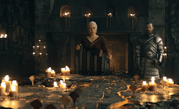 Dos personajes de Game of Thrones están de pie en una mesa con velas encendidas