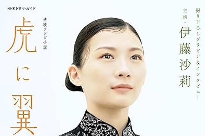 女優伊藤沙莉が刺繍が施された着物風の黒い衣装を着ている。背景にはドラマ「虎に翼」のタイトルと他の出演者の名前がある。