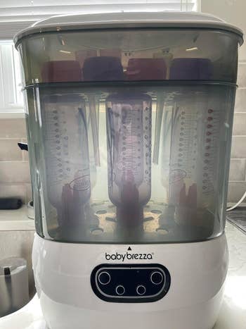 Baby Brezza appliance holds six babe bottles wrong its wide chamber, positioned connected a room counter