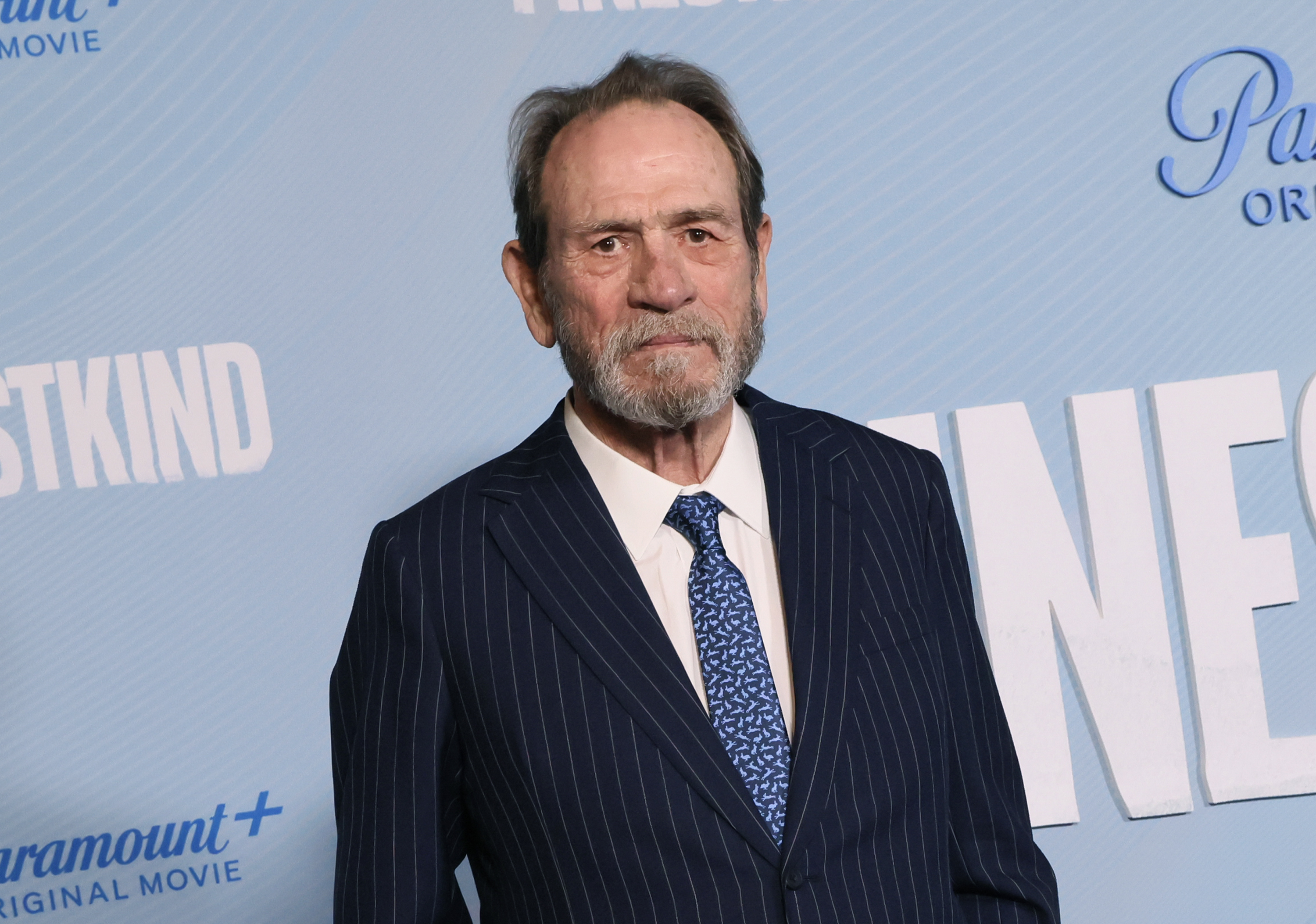 Tommy Lee Jones in a pinstripe suit with a patterned tie at a red carpet event for Paramount+ Original Movie