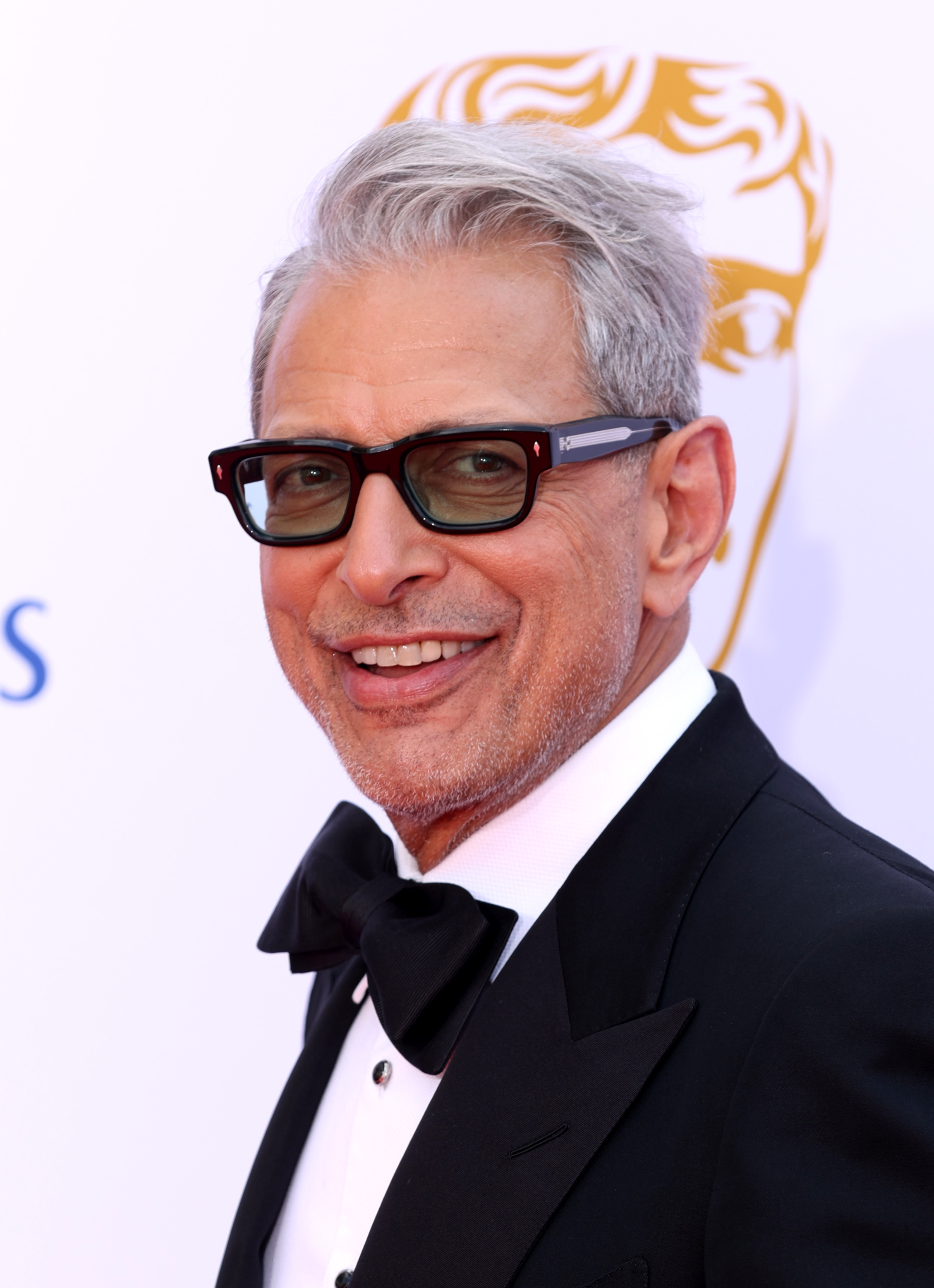 Jeff Goldblum in a tuxedo, smiling on the red carpet at an event
