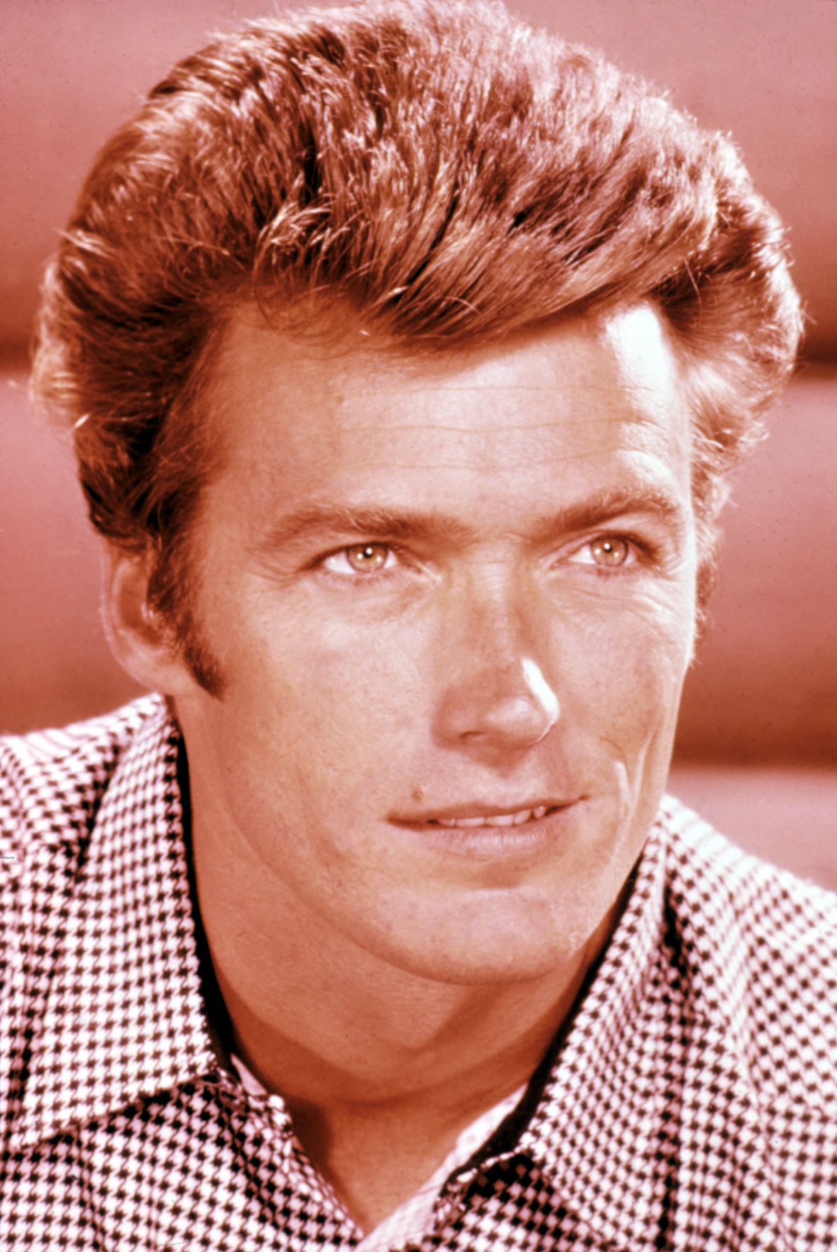 Clint Eastwood in a close-up portrait, wearing a checkered shirt with a slight smile