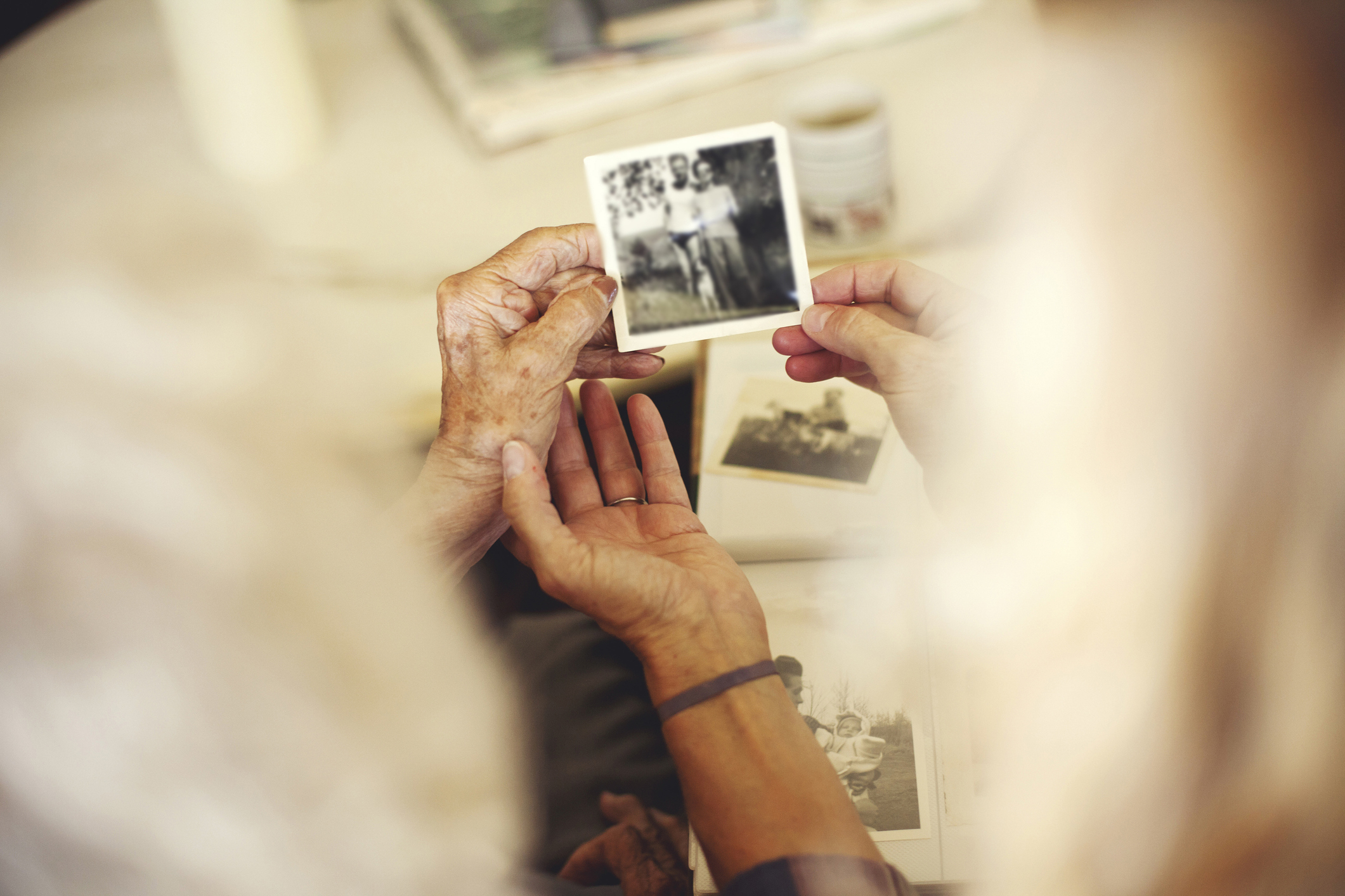Two elderly individuals holding and looking at an old black-and-white photo. The image evokes a sense of nostalgia and memory sharing.