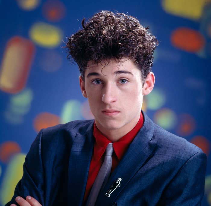 Patrick Dempsey in a suit and tie, posing against a blurred, colorful background