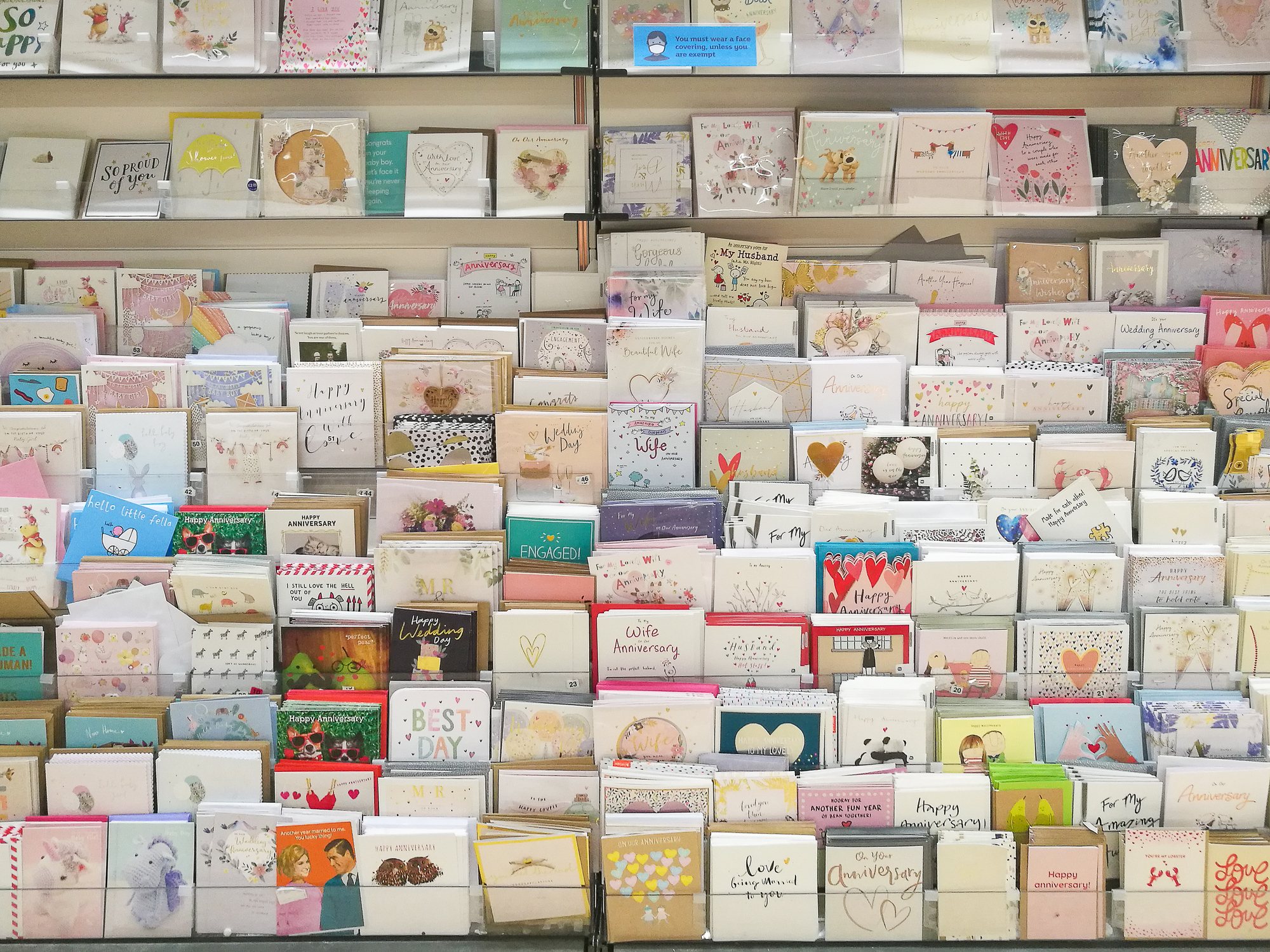 A greeting card display shelf filled with various cards for different occasions such as birthdays, anniversaries, and holidays
