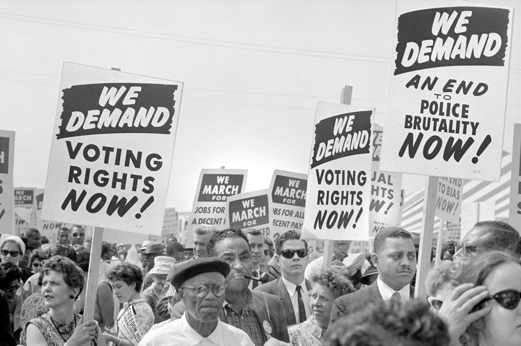 People holding signs reading "We Demand Voting Rights Now!" and "We Demand An End to Police Brutality Now!" during a civil rights march
