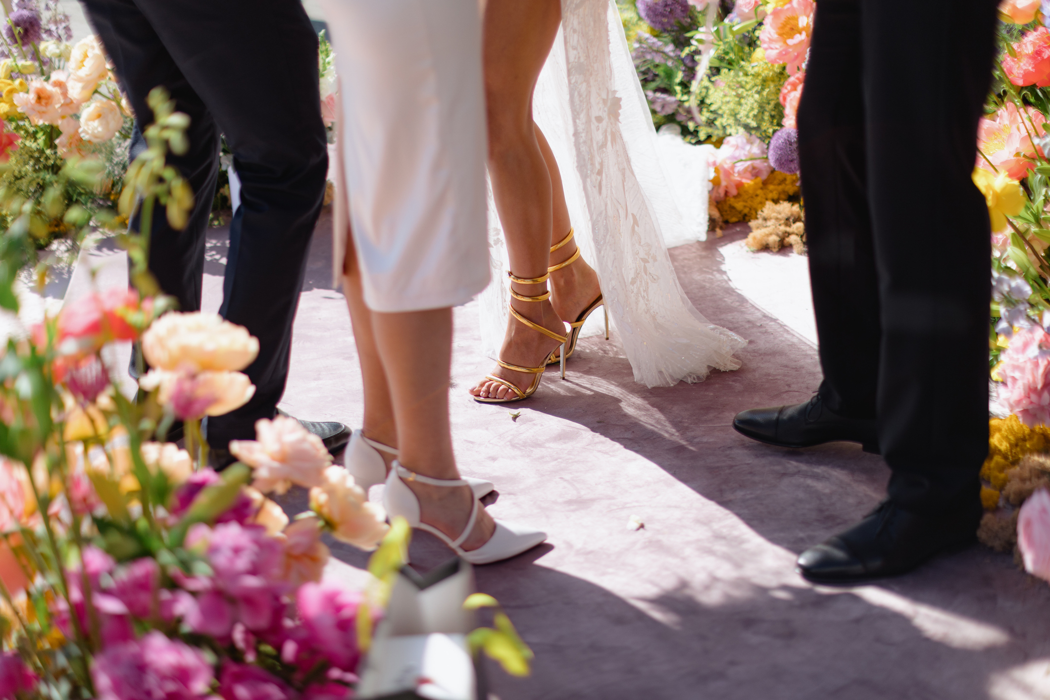 Three unidentified people stand amid vibrant floral decorations at a wedding