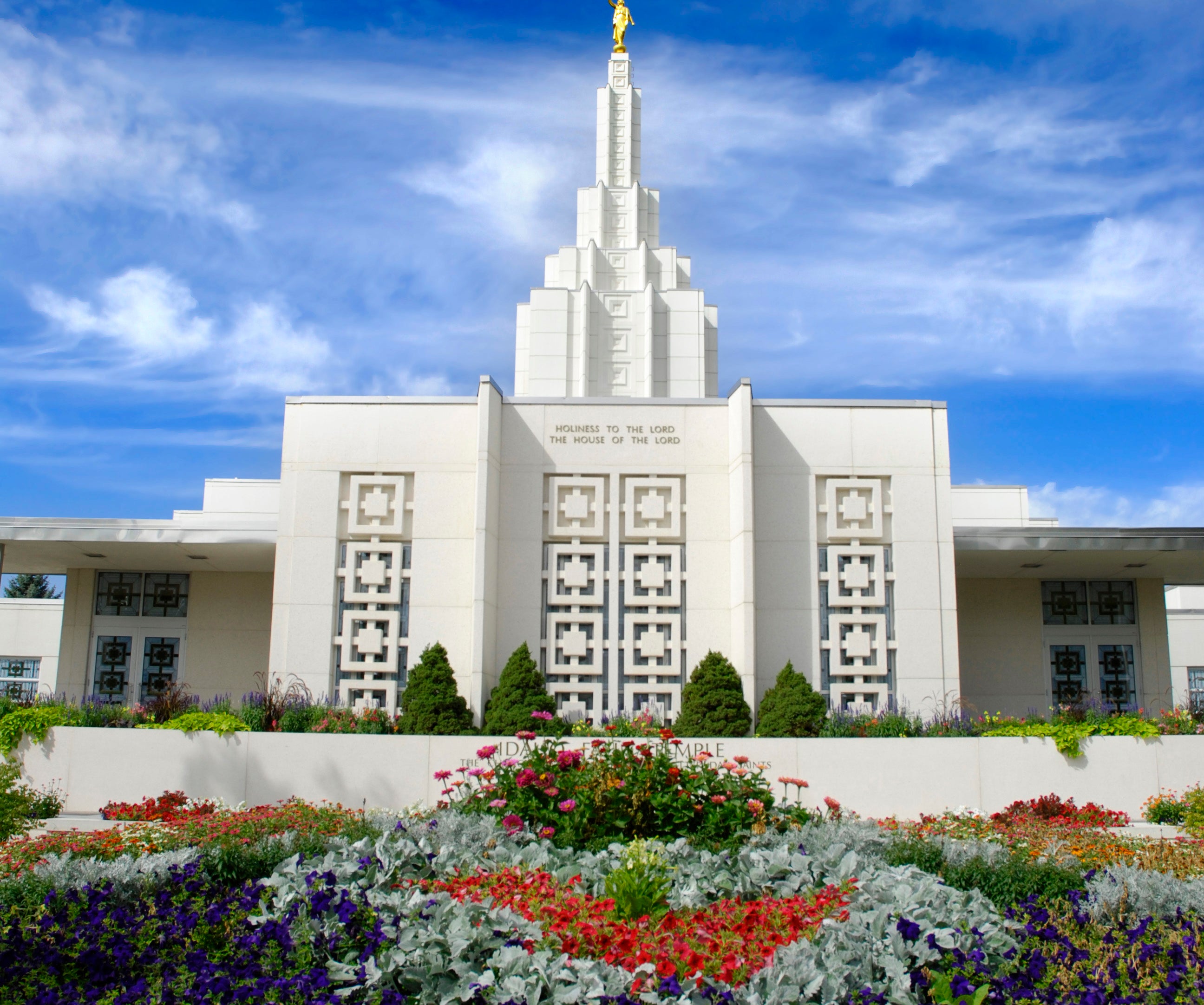 A majestic religious temple with intricate designs stands tall, surrounded by beautifully manicured gardens filled with various flowers and shrubs