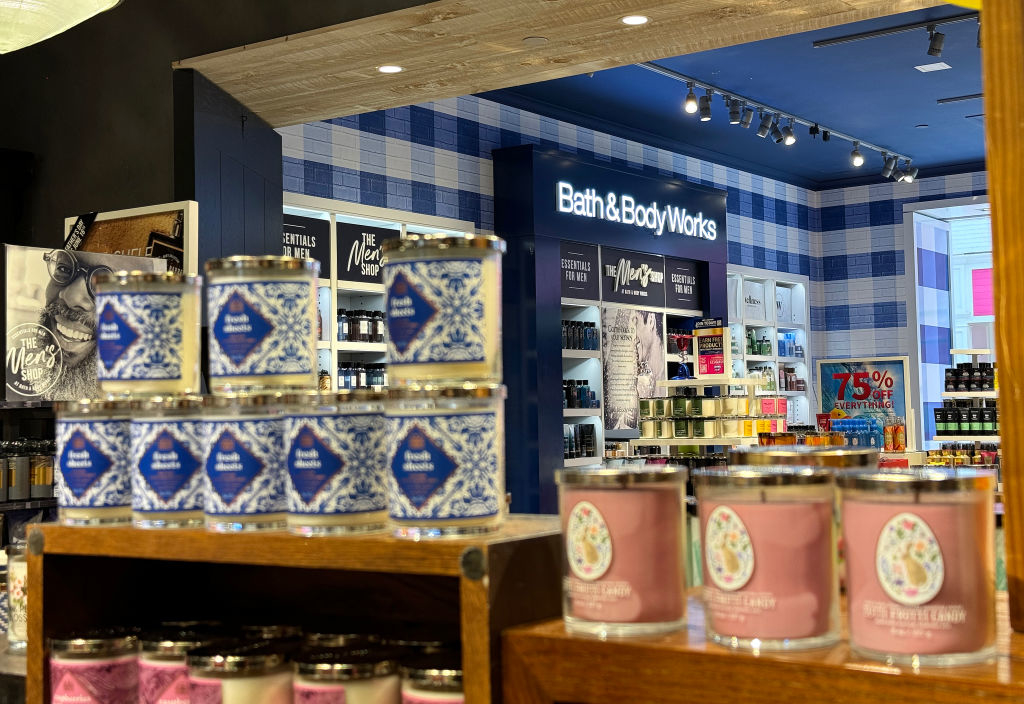 Display of candles and various products inside a Bath &amp;amp; Body Works store, with visible promotions and product arrangements on shelves