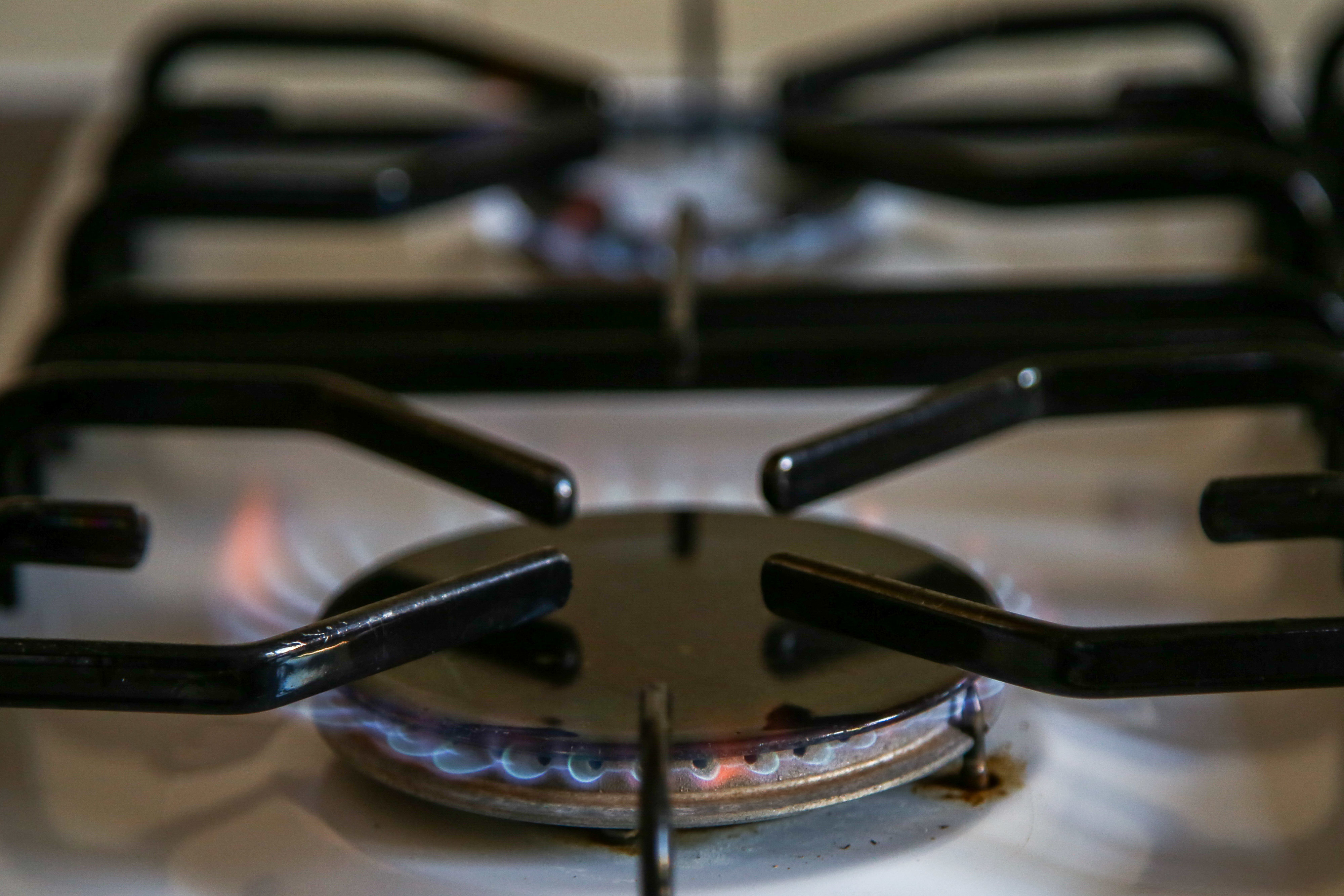 Close-up of a lit gas stove burner with blue flames visible around the edges