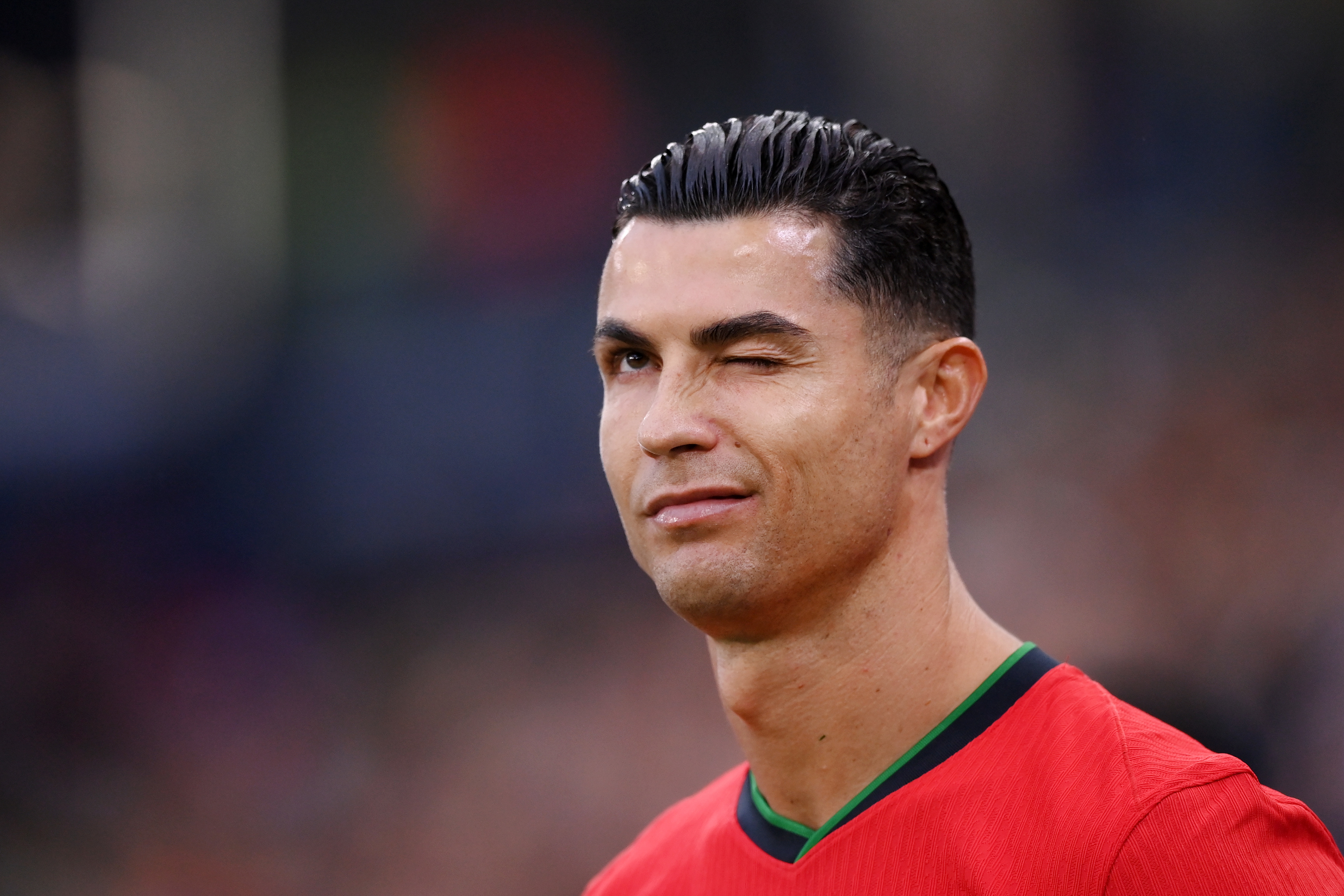 Cristiano Ronaldo winks at the camera, wearing a sports jersey, during a sports event