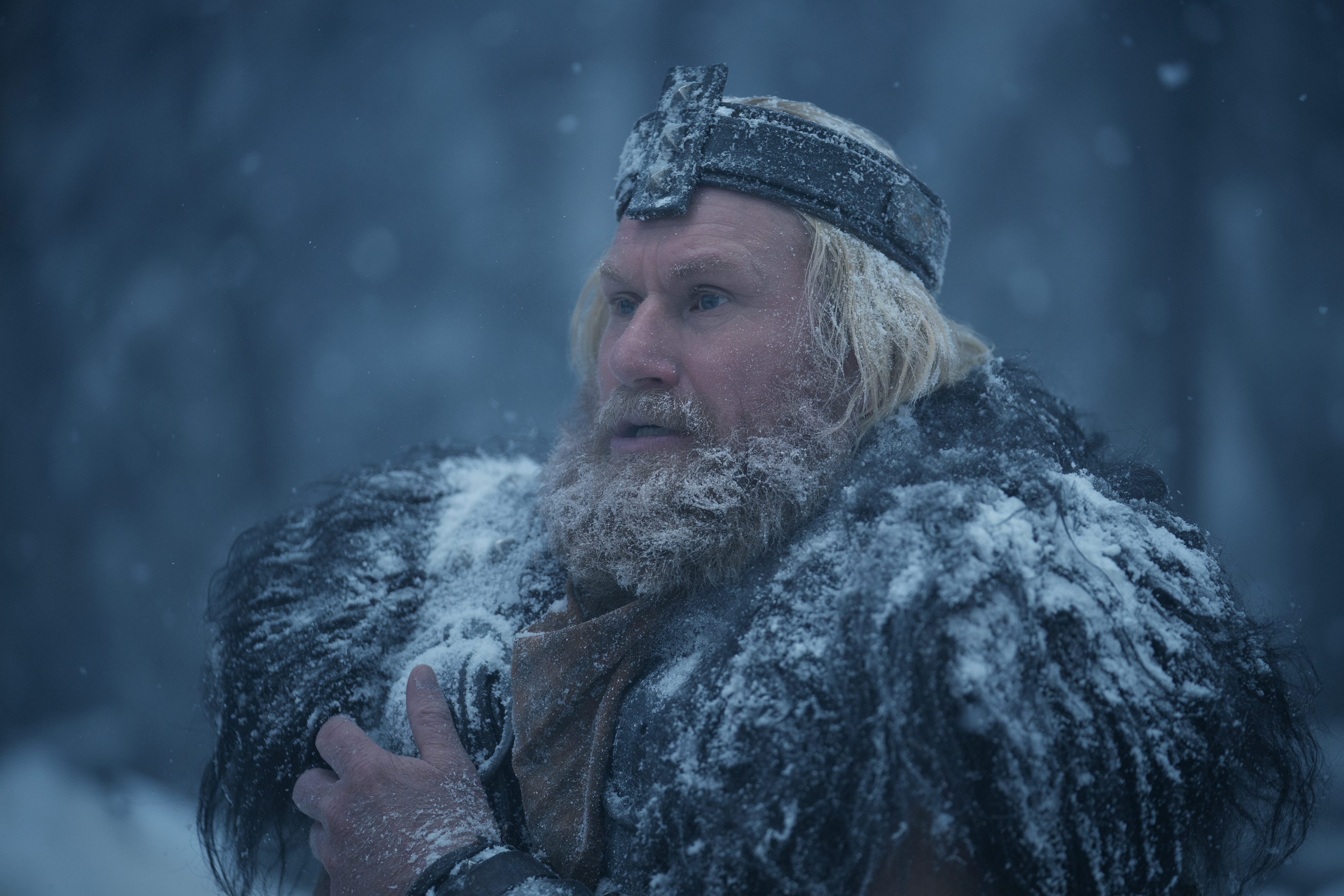 A Viking character stands in a snowy landscape, wearing a fur cloak and a metal headpiece