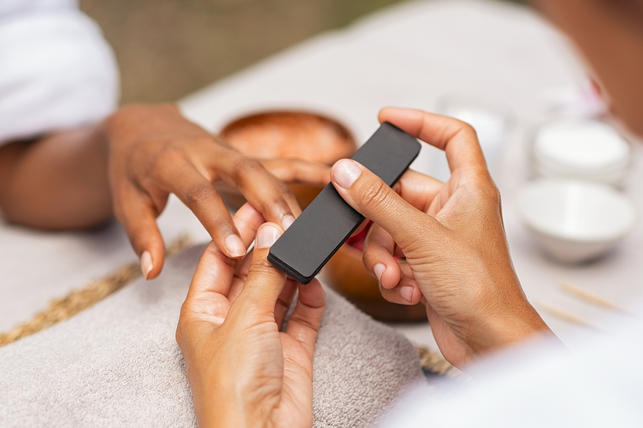 Close-up of a person's fingernails being filed by a nail technician during a manicure session, depicting a work-related and self-care activity