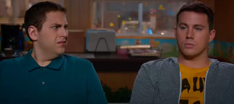 Jonah Hill and Channing Tatum sit next to each other. Jonah looks puzzled, while Channing has a serious expression.