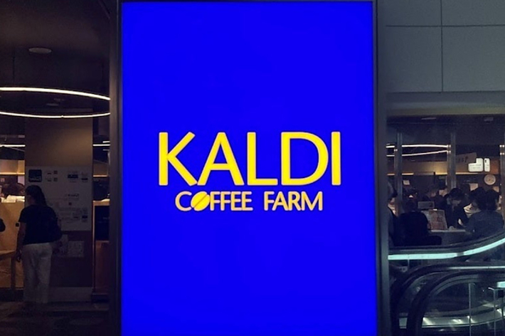 青の背景に黄色で「KALDI COFFEE FARM」と書かれた看板。店舗内は賑わっている様子。