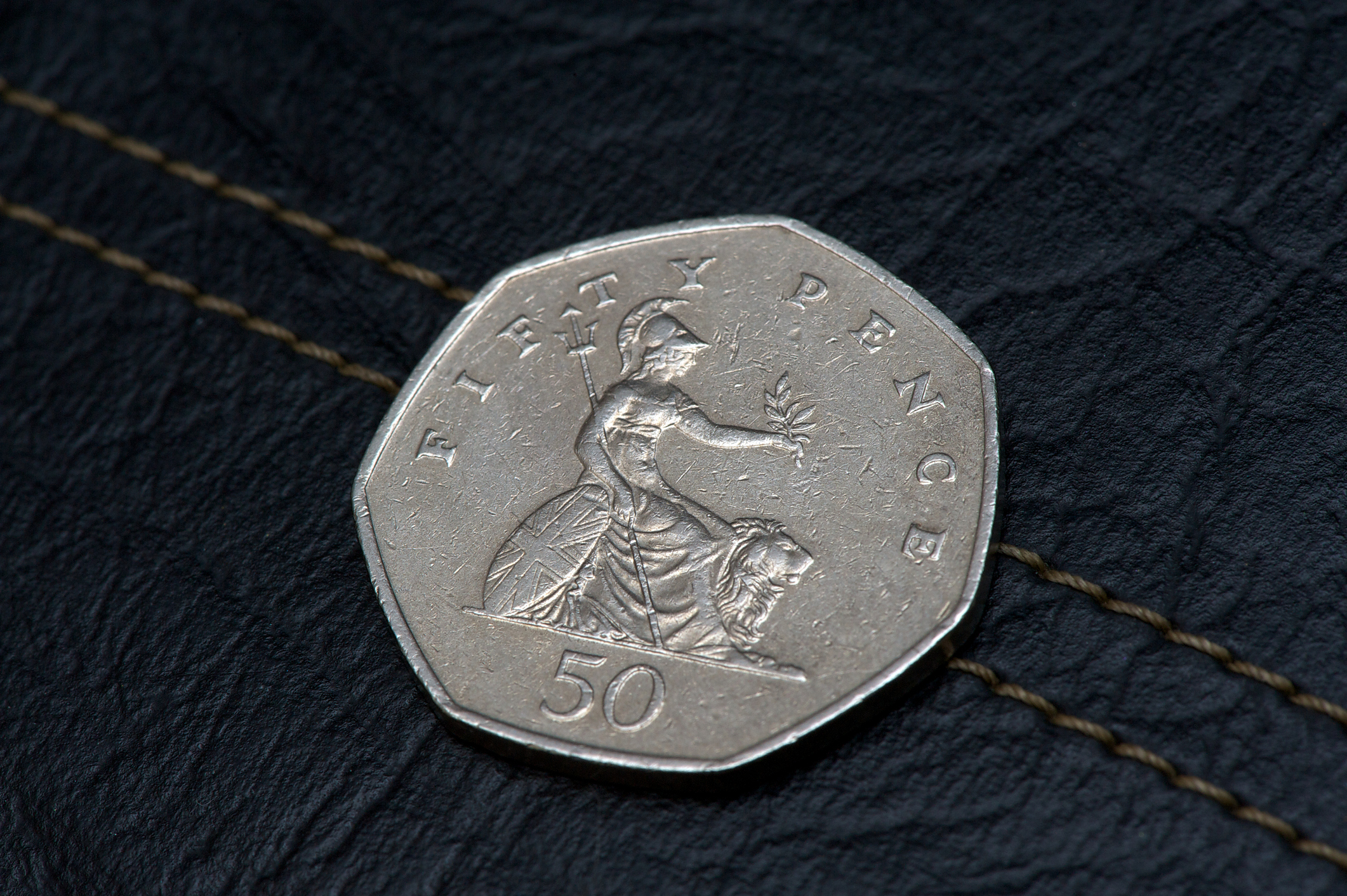 Close-up of a 50 pence coin featuring the figure of Britannia with a lion