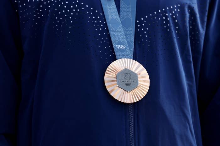 Close-up of a person wearing a blue jacket with an Olympic medal hanging from their neck