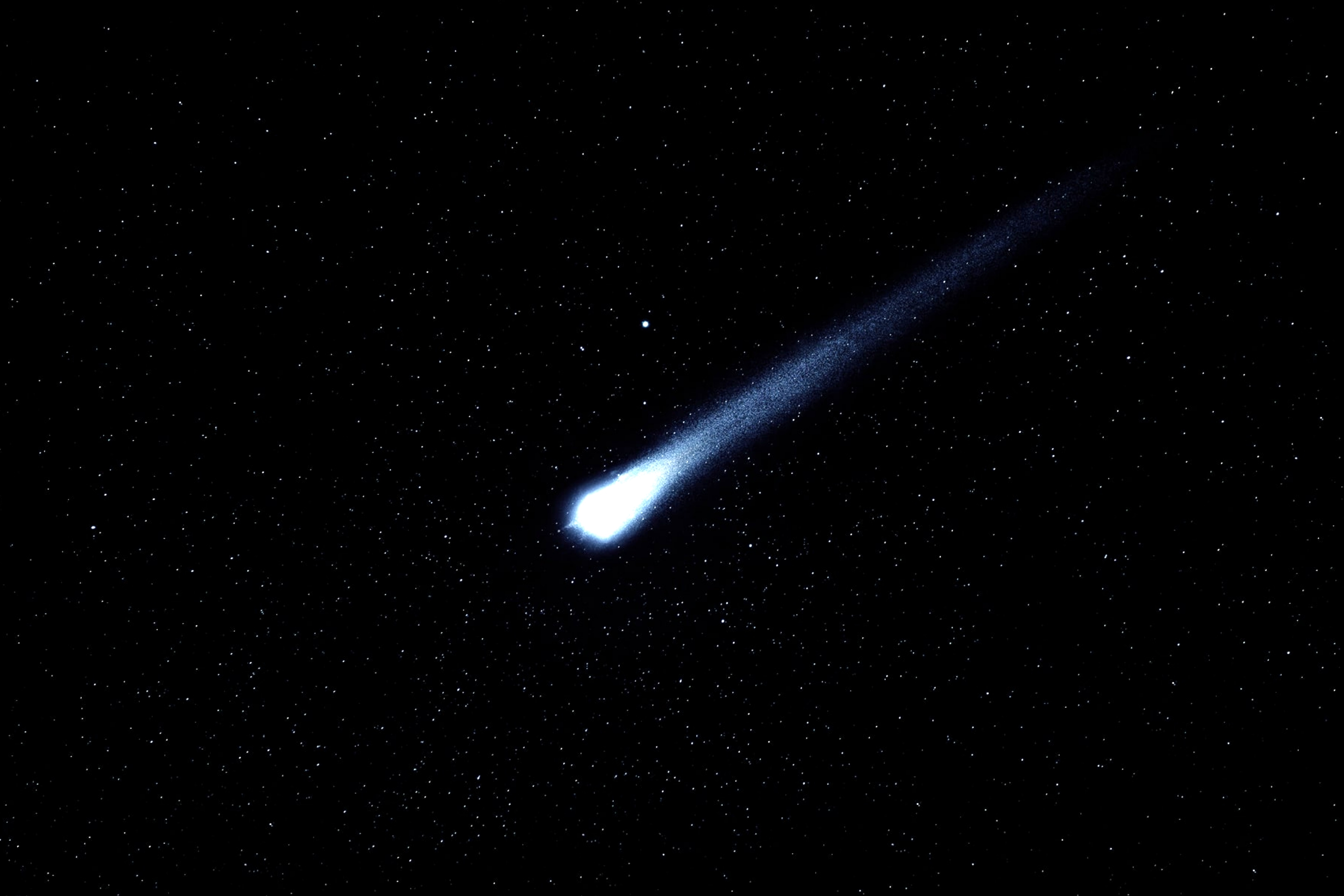 A bright comet with a long tail streaks across a star-filled night sky